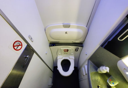 A compact airplane restroom, clean and functional with a no-smoking signの写真素材