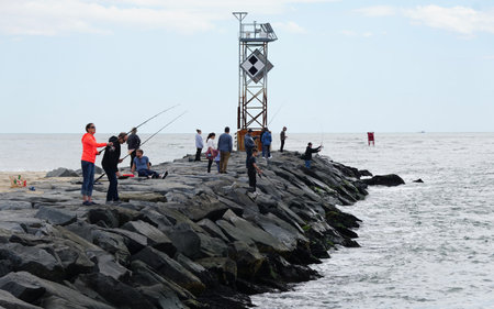 Ocean City, Maryland, U.S.A - May 23, 2025 - Anglers trying their luck on the rocky inlet jetty