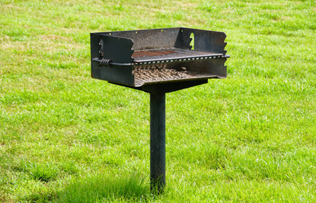 A freestanding metal charcoal grill sits on a grassy patch.の写真素材