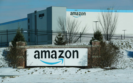 Newport, Delaware, U.S.A - Jan 19, 2026 - A large Amazon warehouse stands behind a black fence, with a brick sign prominently displayed in a snowy landscapeのeditorial素材