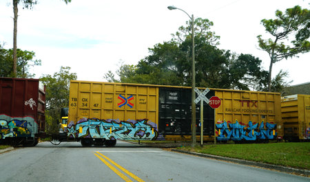 Lakeland, Florida, U.S.A - Jan 2, 2026 - A yellow TBOX freight train covered in colorful graffiti...