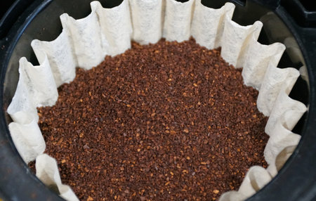 Medium-coarse ground coffee beans settled inside a fluted white paper filter, ready for a fresh drip...