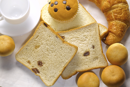 assortment of baked bread and rolls arranged on coarse textured, woven fabric