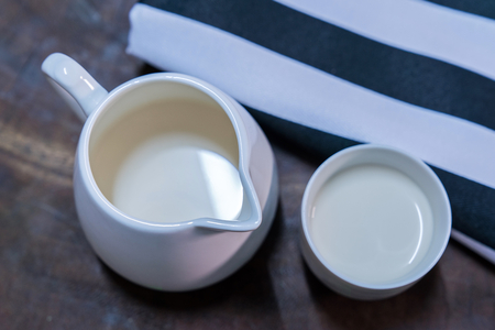 Fresh milk is placed in a white glass placed on an old wood table.の写真素材