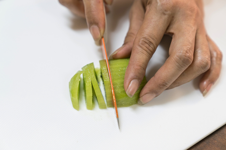 People are cutting kiwi fruit on a white butcher.の写真素材