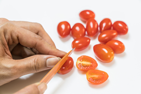 Ripe red tomatoes and knife on cutting board isolated on whiteの写真素材