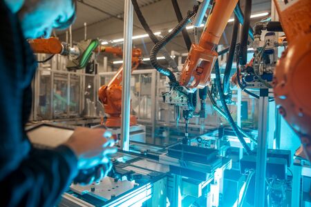 Man programming robot in automotive industrial, professional programmer
