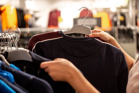 Young woman choosing the clothes in the huge shopping center during big sales