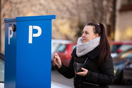 Young woman buying car ticket by cash coinsの写真素材