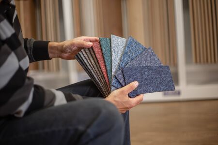 Man choosing the rigt colour of carpet for his new apartment in floor studio, flooring