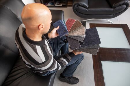 Man choosing the right floor from the floor sampler, swatch in the floor stuido for his new...