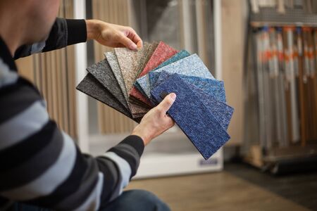 Man choosing the rigt colour of carpet for his new apartment in floor studio, flooring