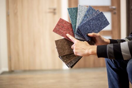 Man choosing the rigt colour of carpet for his new apartment in floor studioの写真素材
