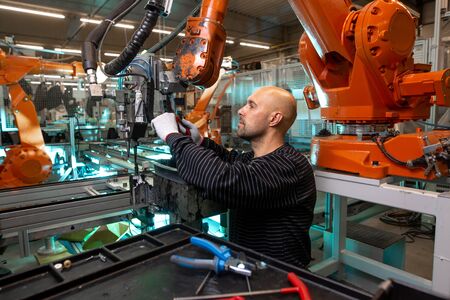 Engineer doing maintenance on a automatic robot arms in automotive industrial, smart factoryの写真素材