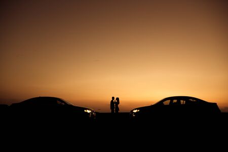 Loving couple enjoying full of love during lovely summer sunset with their same cars, love concept