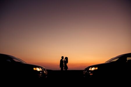 Loving couple enjoying full of love during lovely summer sunset with their same cars, love conceptの写真素材