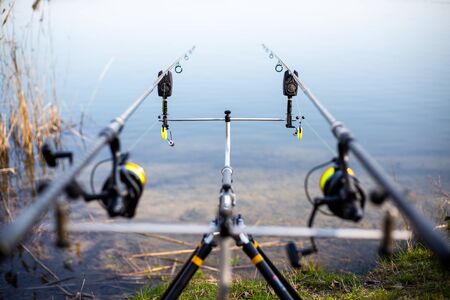 Close up of rack with fishing rods by the lake, fisherman waiting for freshwater fish, fishing background, angling sportの写真素材