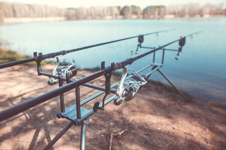 Two cast fishing rods on the rack by the lake, ready for fishing, carpfishing, angling, sport conceptの写真素材