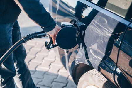 Man refueling a car during low fuel rates, fuel prices, transport conceptの写真素材