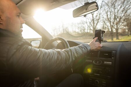 Man setting up GPS on the mobile before his drive, asisstant during driving the car