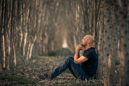 Sitting man with depression going through a rough patch in his life, suffering from mental exhaustion, anxiety, burnoutの写真素材