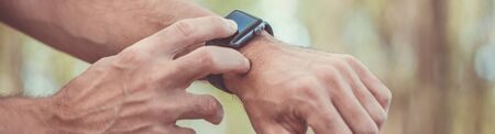 Macro concept of man clicking, pointing on a screen of his generic design smart watch, blurred...