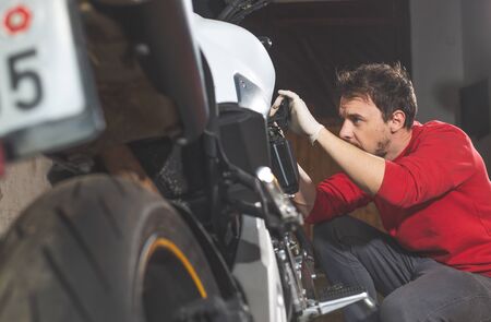 Man repairing, doing maintenance of his motorcycle, motorbike in the garage, reapir concept