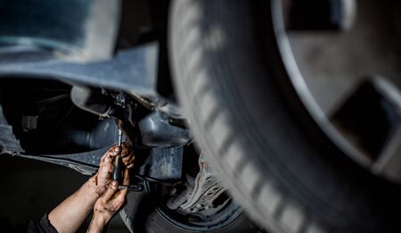 Car mechanic doing repair, maintenance oil change to the car on hydraulic car lift, car vehicle serviceの写真素材