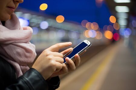Young woman calling on a mobile at train station during early morning
