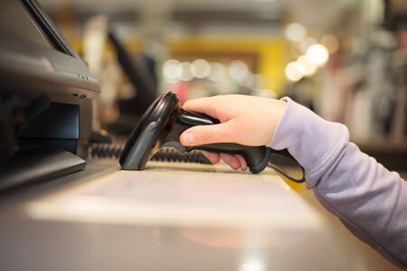 Young woman hands using scanner for scanning goods to a pos for a customer at huge shopping center, finance conceptの写真素材