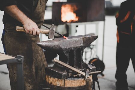 The blacksmith manually forging the molten metal on the anvil in smithy with spark fireworks, artworkの写真素材
