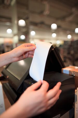 Young woman printing some invoice, receipt for a costumer at huge shopping centerの写真素材