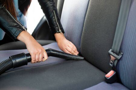 Woman cleaning, vacuuming interior of car by vacuum cleaner, transport conceptの写真素材