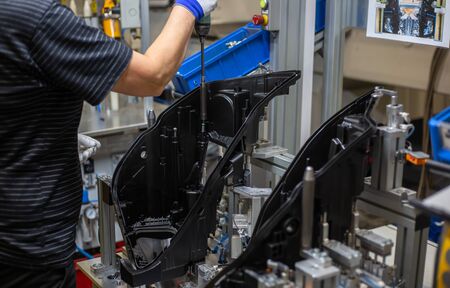 Production operator assembling frontlight headlamp, headlight for vehicle or a car in automotive...