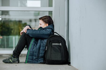 Little boy or child sitting alone on floor in front of the school after suffering an act of bullyingの写真素材