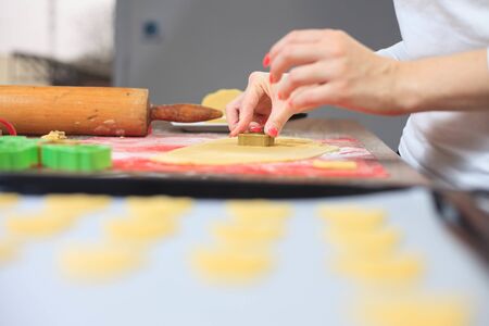 Young hands cutting ginger dough at modern kitchen