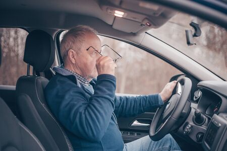 Senior man putting on glasses before driving, his eyesight is not good, safety and transportation...