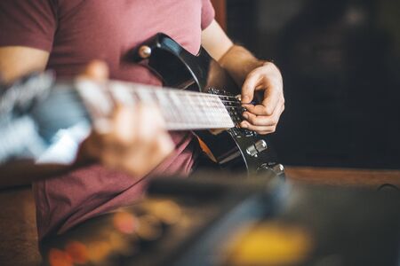Close up hand of young man playing on a professional, black electric guitar, music instrument, entertainment, lifestyleの写真素材