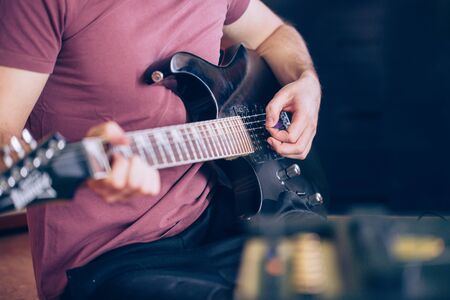 Close up hand of young man playing on a professional, black electric guitar, music instrument, entertainment, lifestyleの写真素材