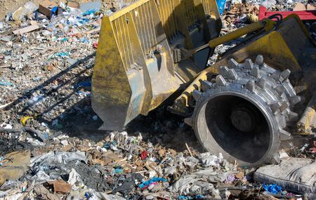 Close up of bulldozer working on the huge landfill or garbage dump pile, pollution conceptの写真素材