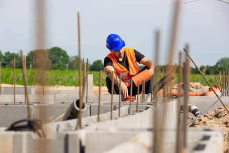 Construction or site manager checking or overseeing the foundations of the new house, buidling or...