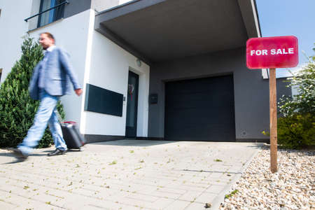 Sitting man without work in front of the house during economic crisis, selling real estate