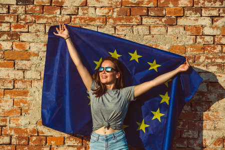 Young happy woman holding european union flag, promotion of the EU, policy conceptの写真素材