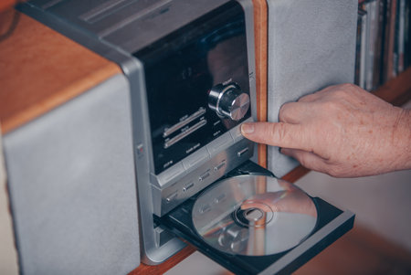 Senior man inserting a CD to the hi-fi station and listening the musicの写真素材