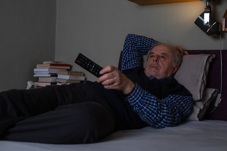 Senior man relaxing ot resting and watching a TV late at night at homeの写真素材