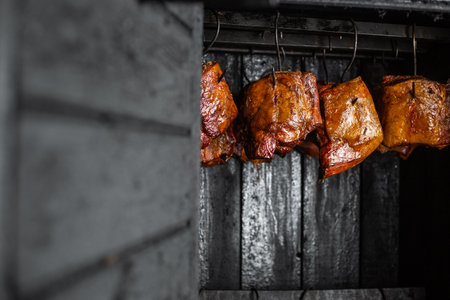 Close up of smoked meat and belly or beech meat with dark crust in the smokehouse or smoker, food conceptの写真素材
