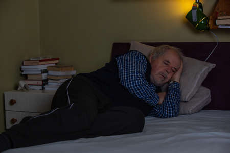 Senior man fell asleep during watching a TV or television at midnight, sleeping conceptの写真素材