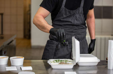 Chef preparing dish to a box in the restaurant for food delivery service to home, online orderingの写真素材