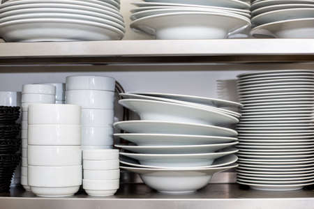 White plates and bowls in the kitchen shelf at the restaurantの写真素材