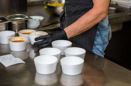 Chef preparing soup to a box in the restaurant for food delivery service to home, online orderingの写真素材